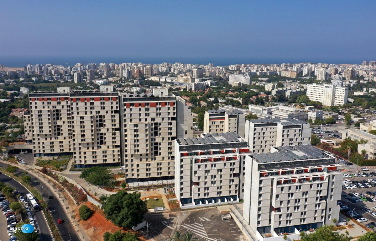 נוף עירוני עם בנייני מגורים גבוהים ונוף ים ברקע.